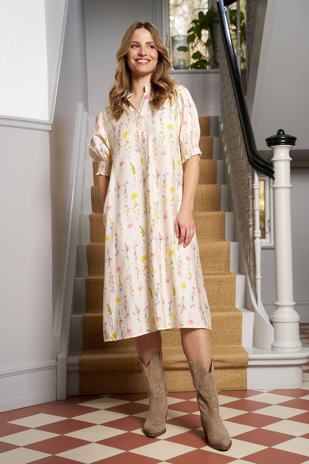 Beige midilang kjole med smockærmer og blomsterprint, kombineret med beige ruskindsstøvler.