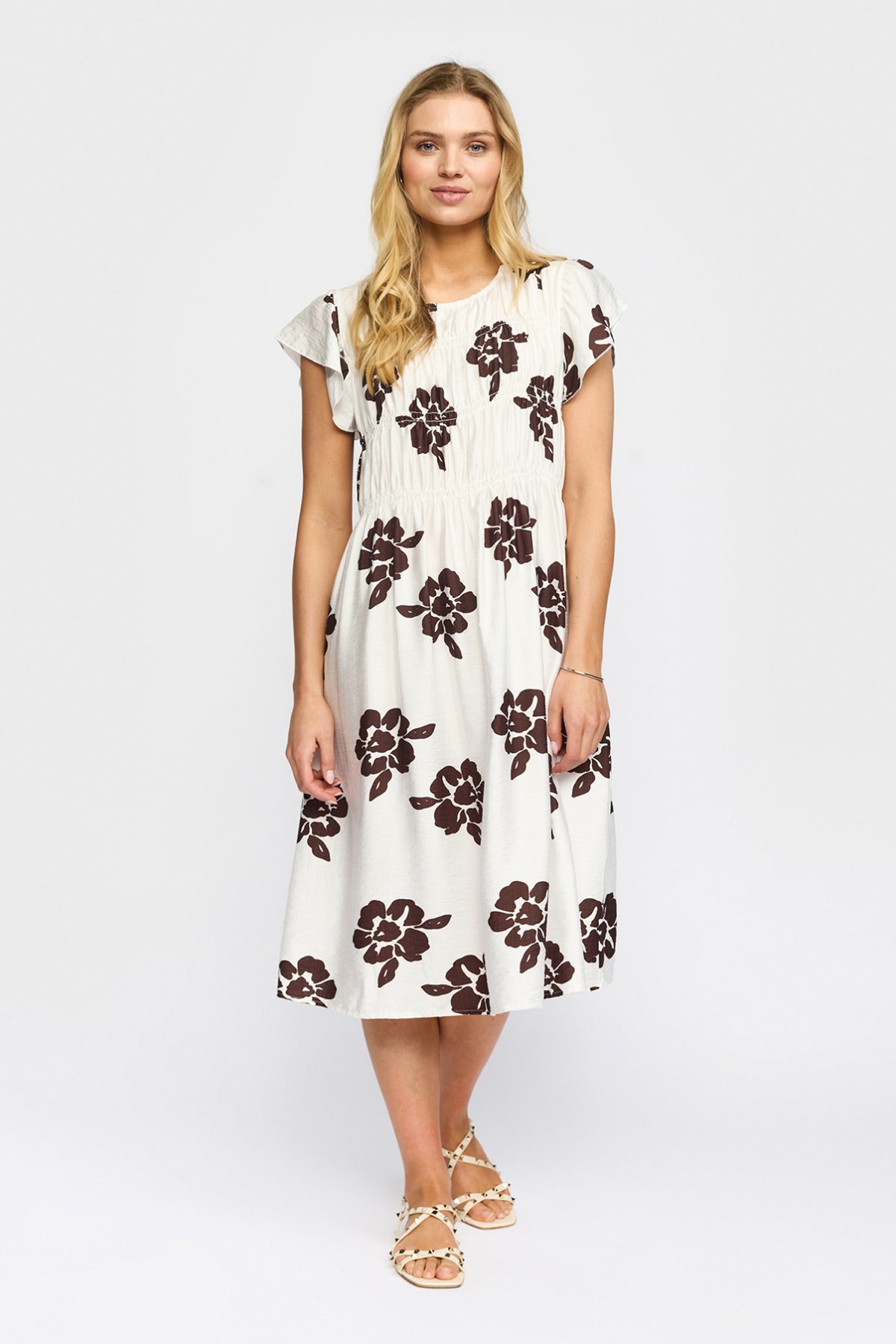 Kortærmet hvid kjole med brune blomsterprint og rund hals, midilængde.