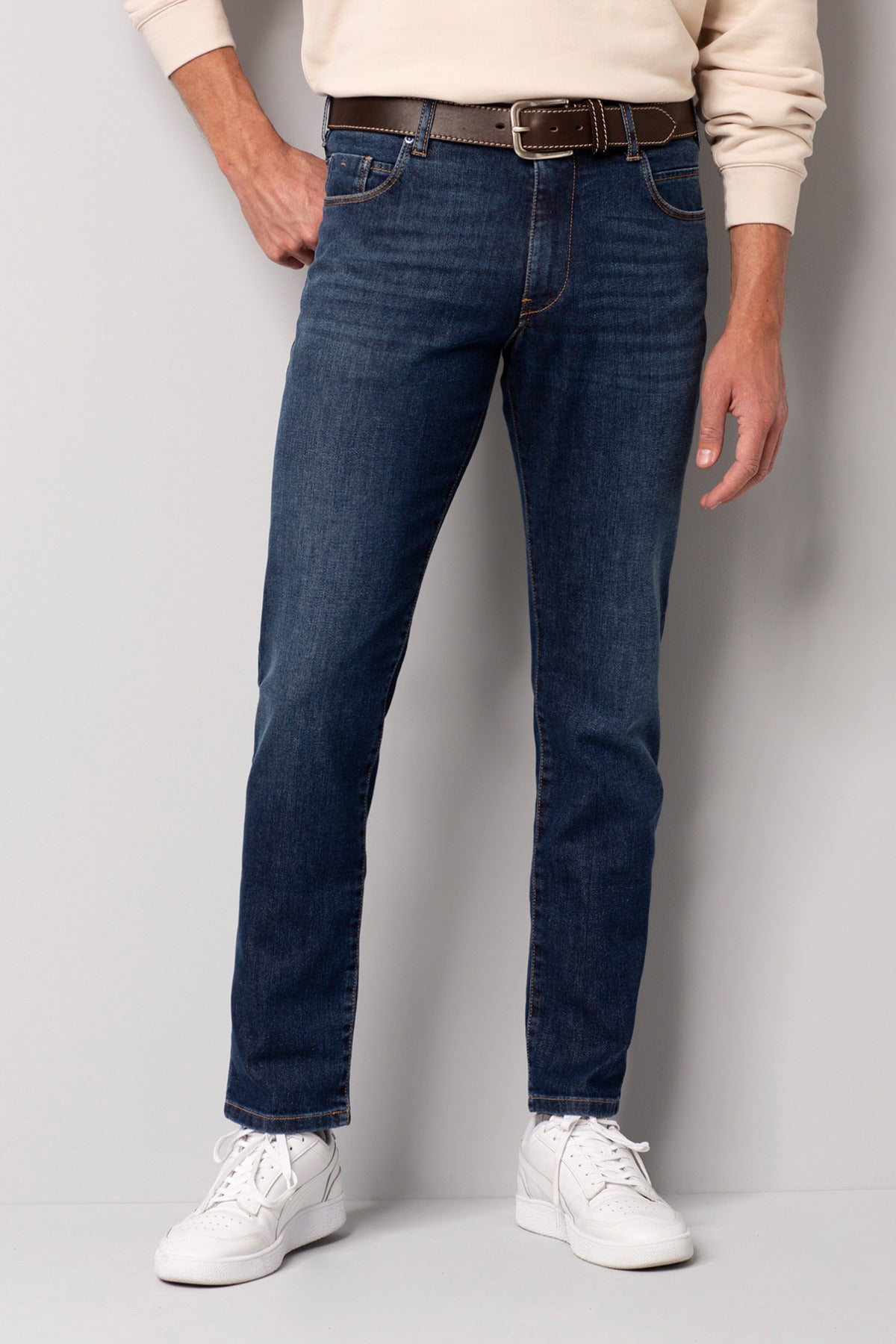 Mørkeblå slim fit jeans med syet detalje og lommer, båret med hvidt bælte og sneakers.