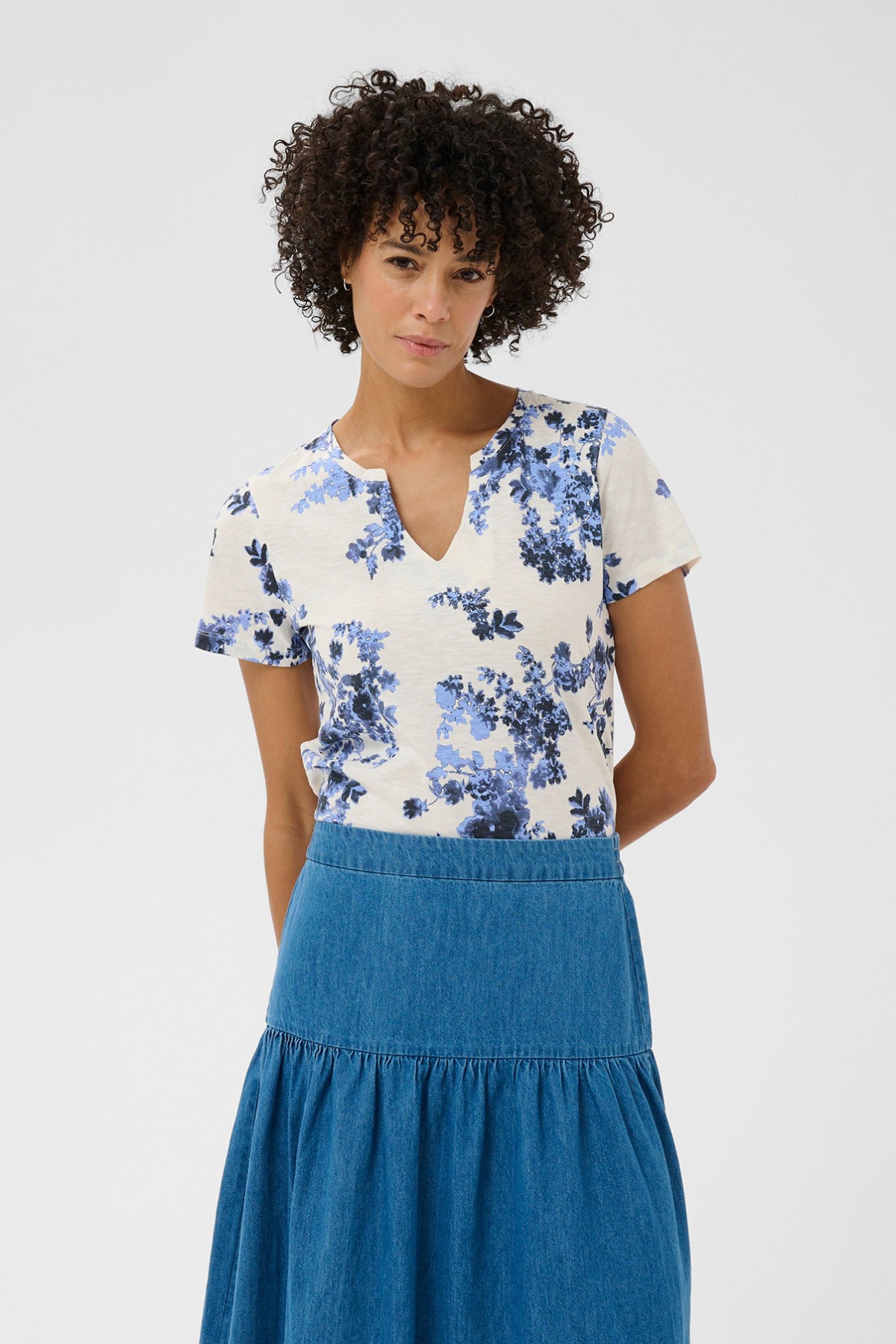 Hvid kortærmet bluse med blå blomsterprint og V-udskæring.