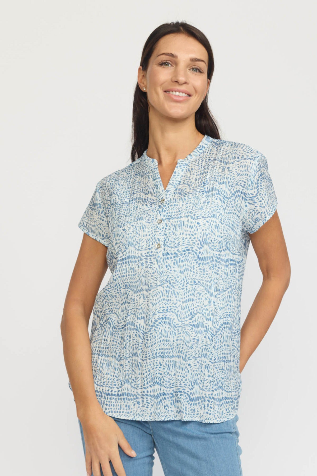 Kortærmet let bluse med blå og hvidt paisley-print og små knapper ved halsen.