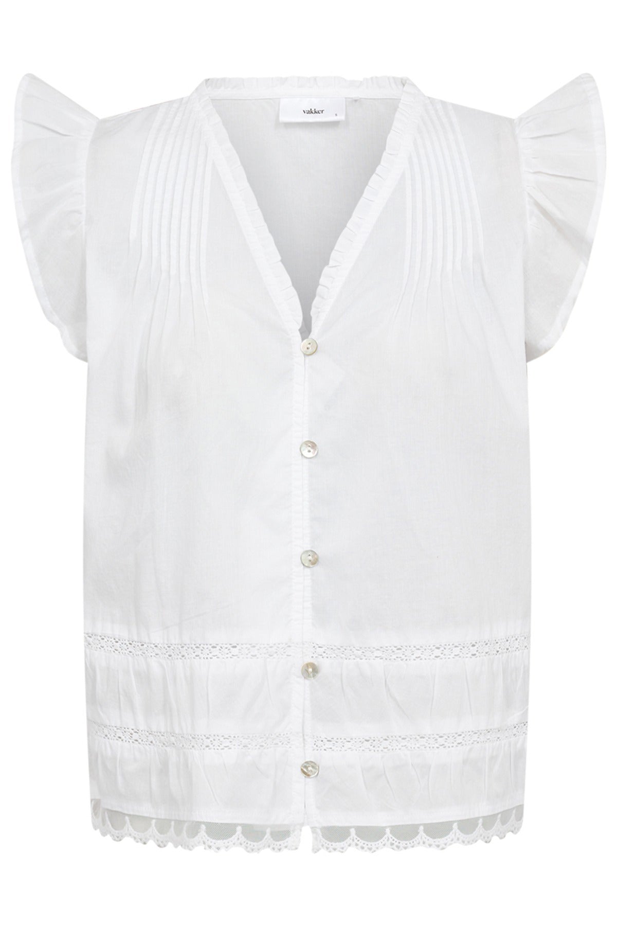 Hvid skjortebluse med flæser på ærmekanter, broderidetaljer og perlemorsknapper.