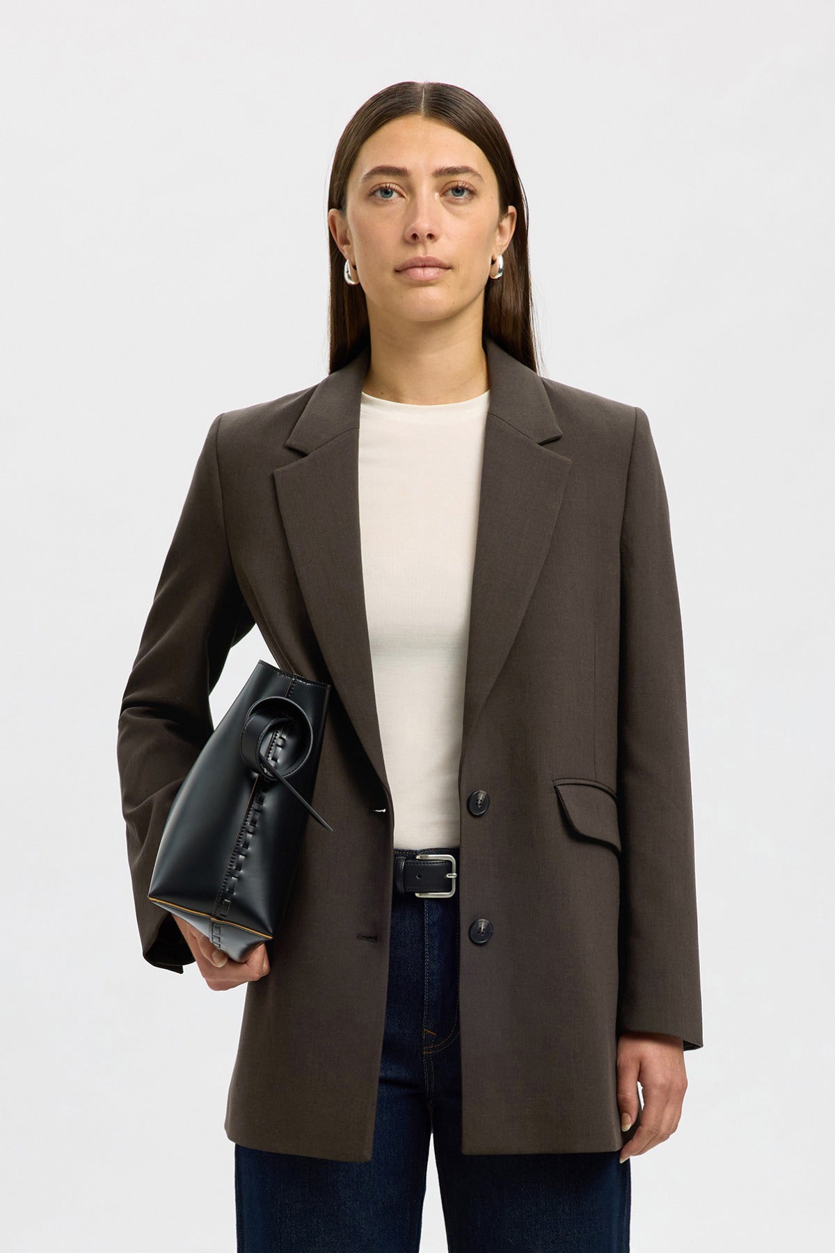 Brun afslappet blazer med revers og knapper, stylet med hvid top og sort taske.
