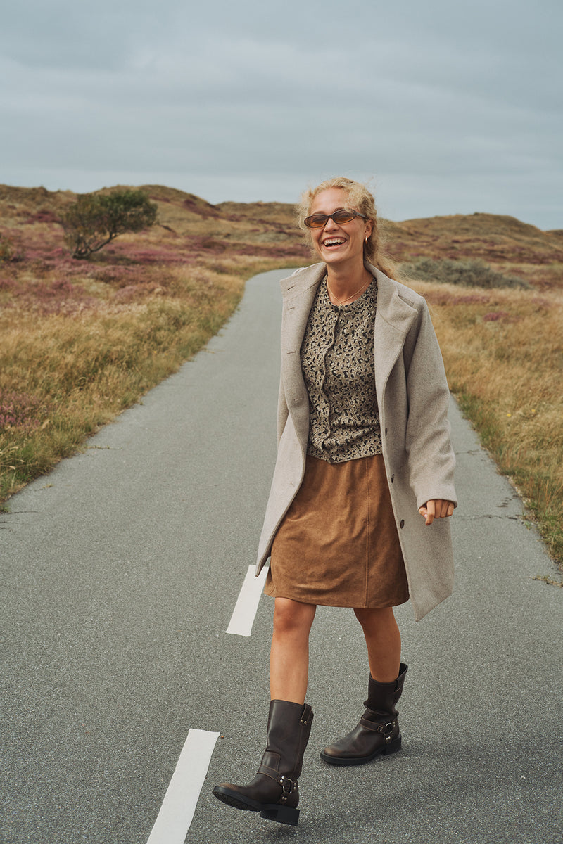 Lysebrun cardigan med leopardprint og løstsiddende pasform, stylet med brun ruskindnederdel og sorte støvler.