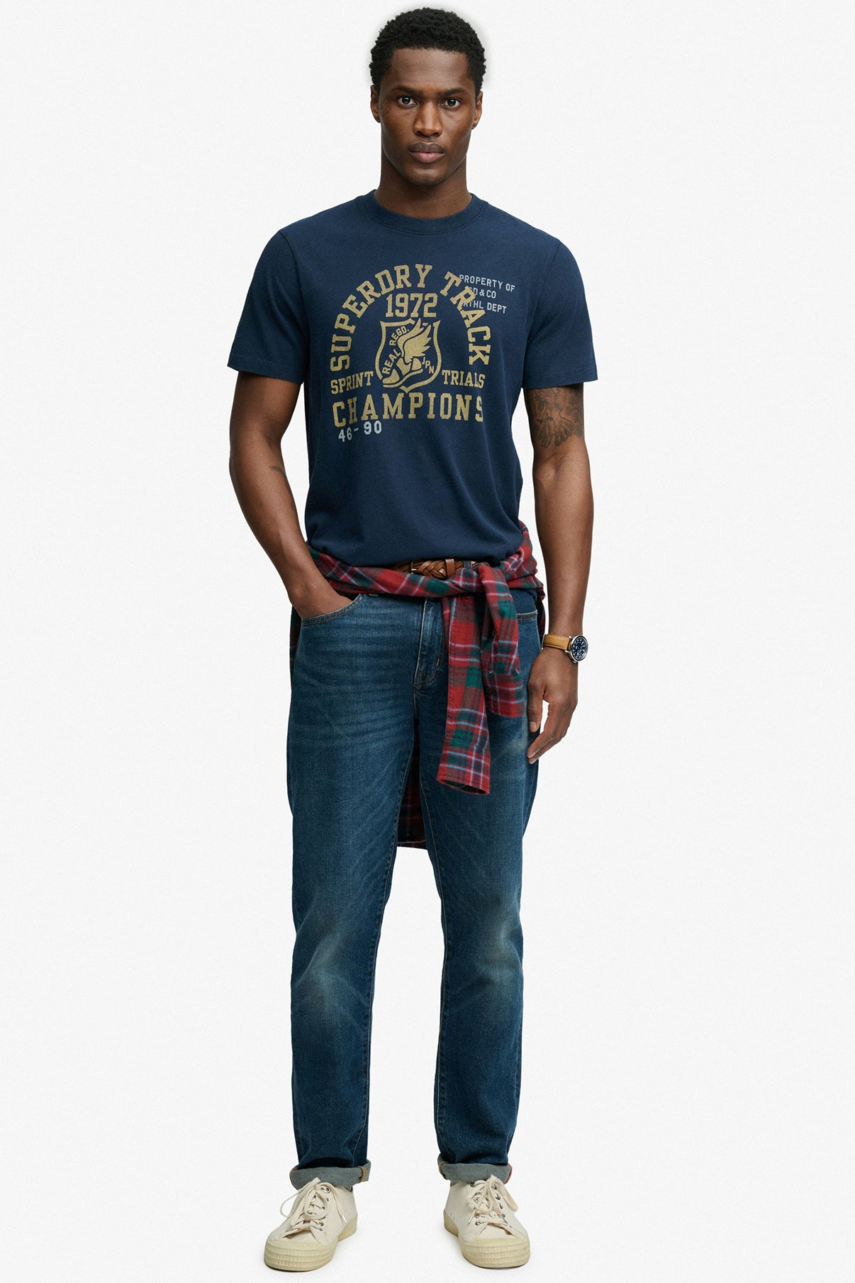 Mørkeblå t-shirt i relaxed fit med gul print, båret med blå jeans og ternet skjorte bundet om livet.