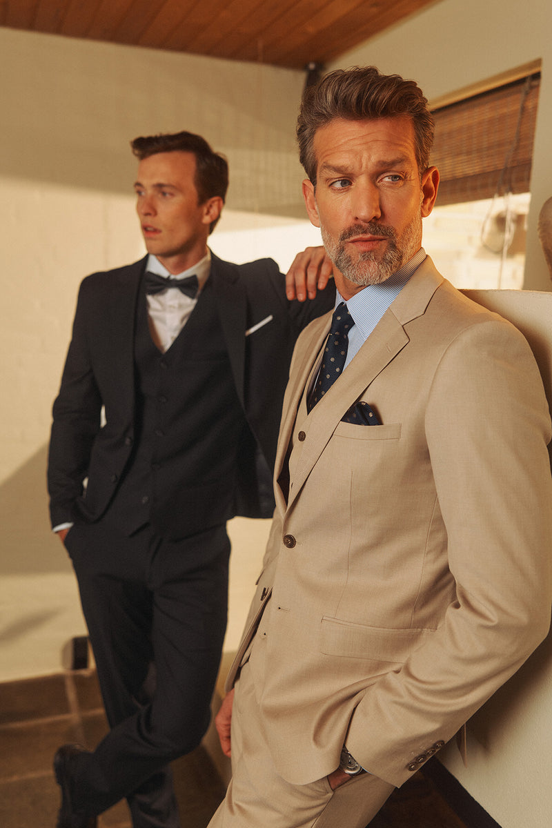 Beige vest med paspolerede lommer, lyseblå skjorte og blå slips, elegant herrestil.