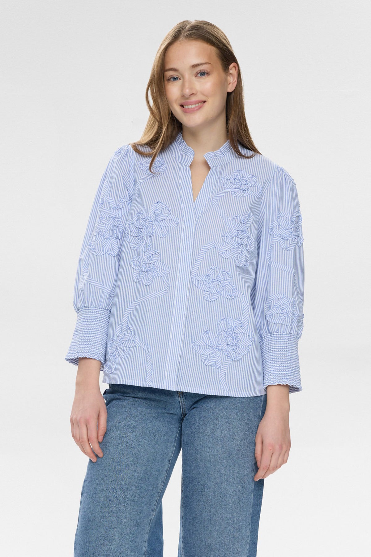 Lyseblå stribet bluse med broderede detaljer og let puffede ærmer.