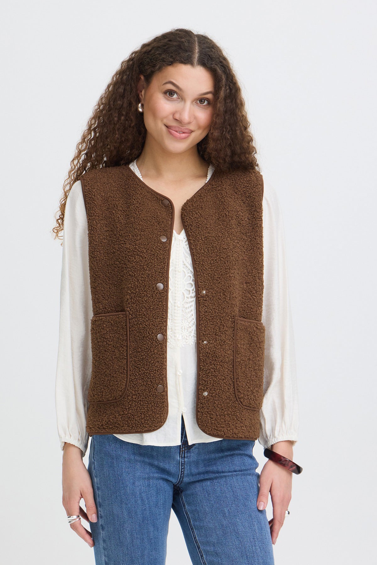 Brun teddyvest med knapper og lommer, let oversize pasform over hvid bluse.