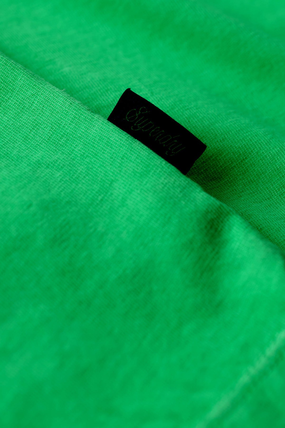 Neongrøn T-shirt i bomuld med sort logoetiket ved sømmen.