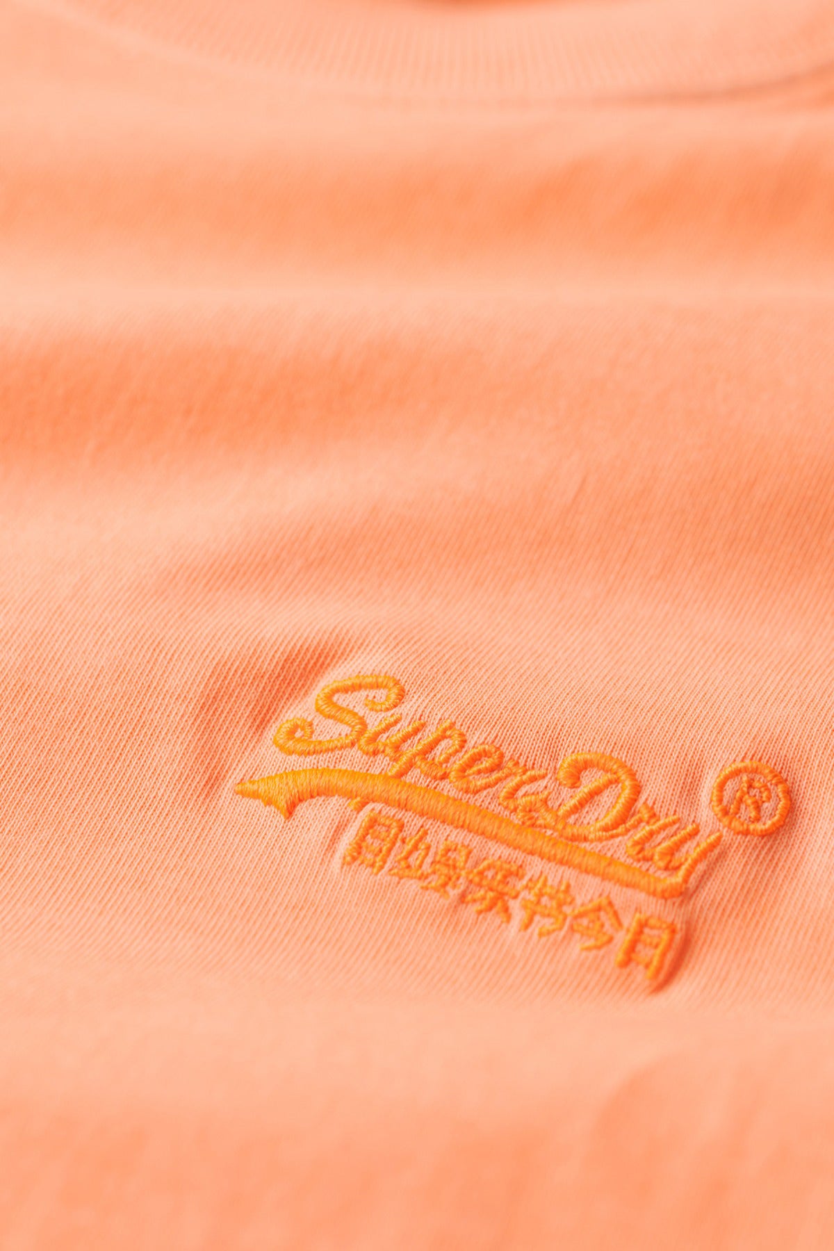 Lyserød t-shirt med orange broderet SuperDry-logo på brystet lavet af blødt bomuld.
