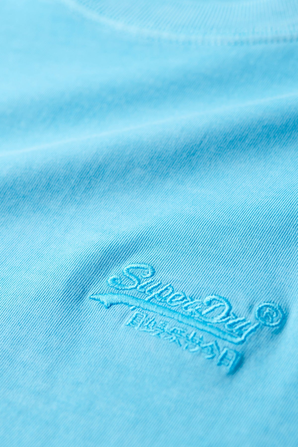Blå T-shirt med ton-i-ton broderet Superdry-logo på brystet.