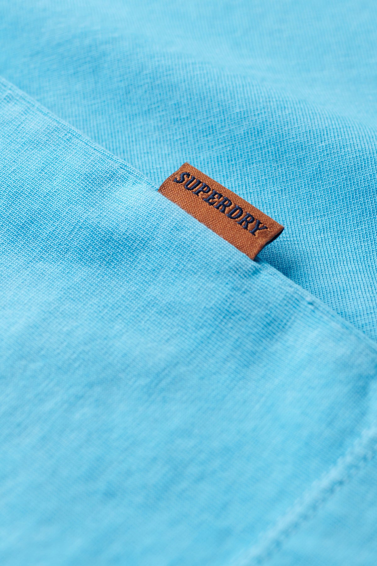 Lyseblå t-shirt med lille brun Superdry-logo på brystlomme i bomuld.