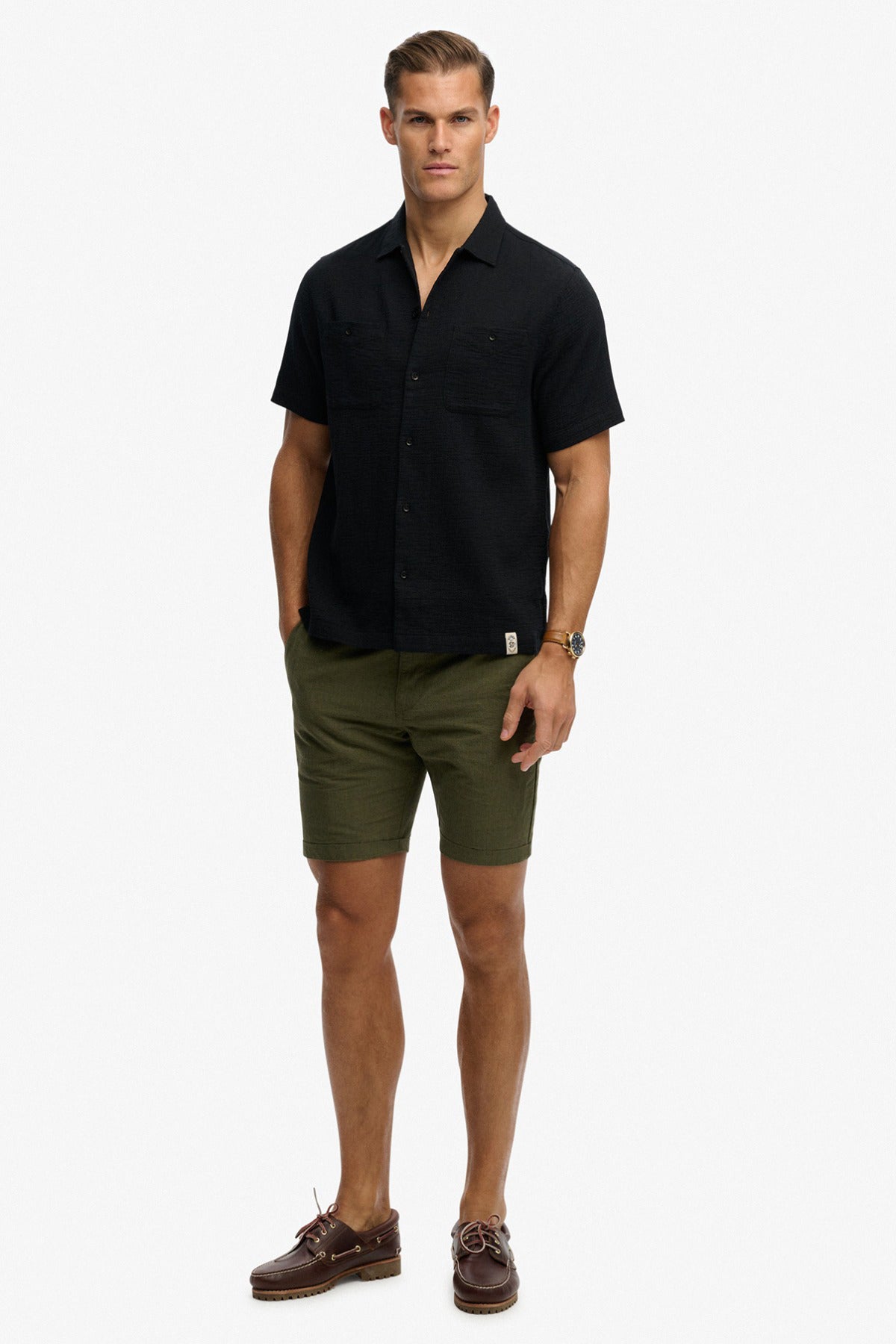 Sort kortærmet skjorte med to brystlommer og åben krave, båret med olivengrønne shorts.