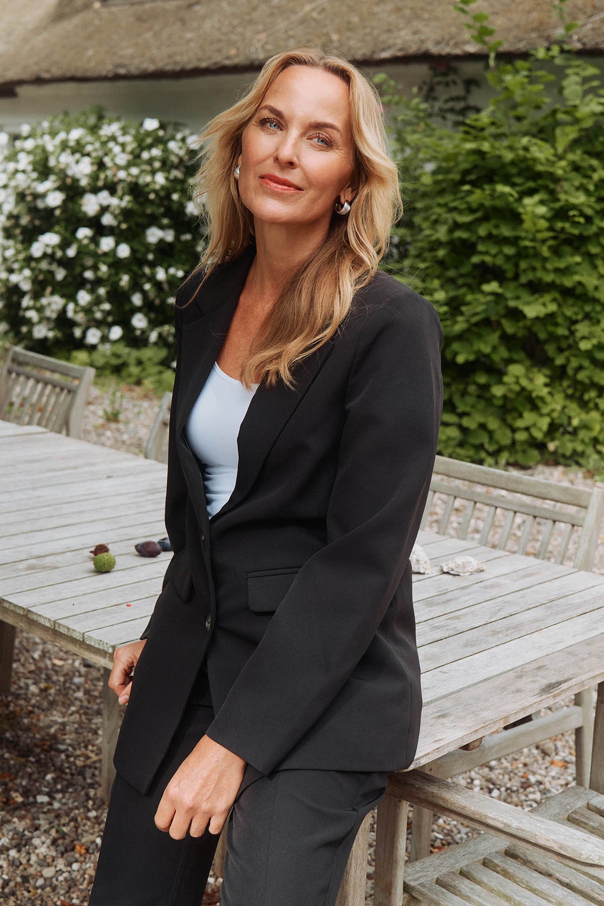 Sort klassisk blazer til kvinder med revers, mørke knapper og sidelommer, tætsiddende pasform.