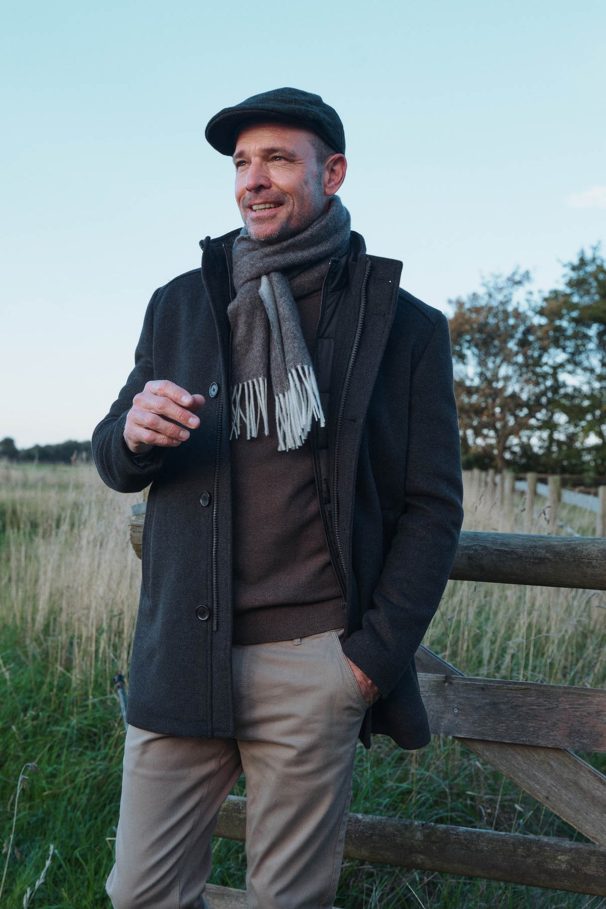 Mand i mørkeblå uldfrakke med tørklæde og aftageligt quiltet inderstykke.